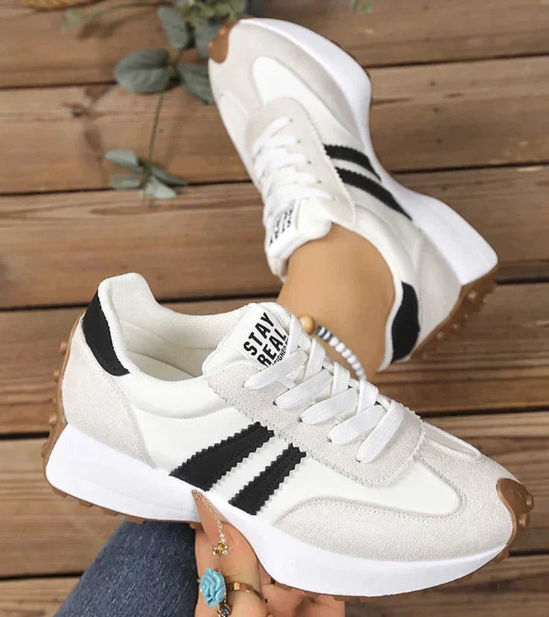 White and gray sport sneakers with black stripe accents, lace-up, cushioned sole