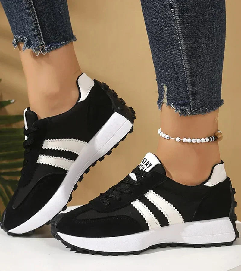Black and white lace-up sport sneakers with three stripe detail and thick rubber sole