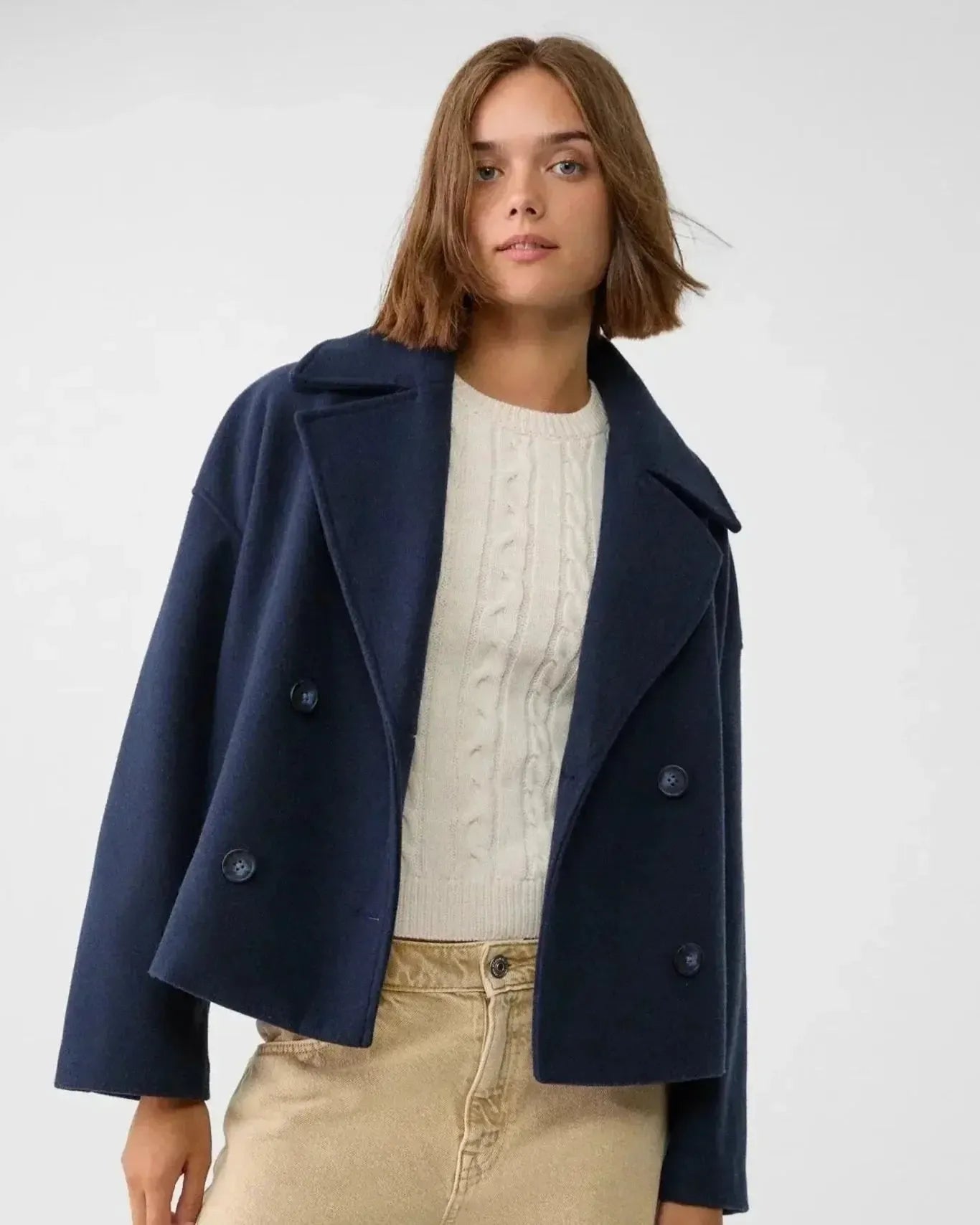 Navy double-breasted coat with wide lapels and buttoned flap pockets.