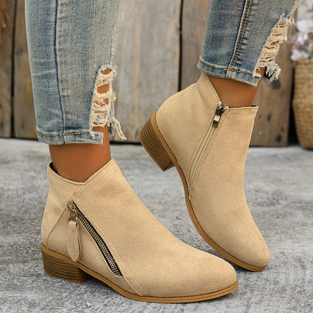 Beige suede orthopedic ankle boots with side zipper and low wooden block heel.