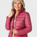 Magenta puffer jacket with full zipper and stand collar, worn with long sleeves.