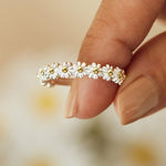 Silver daisy-styled ring with gold-centered flowers across the band