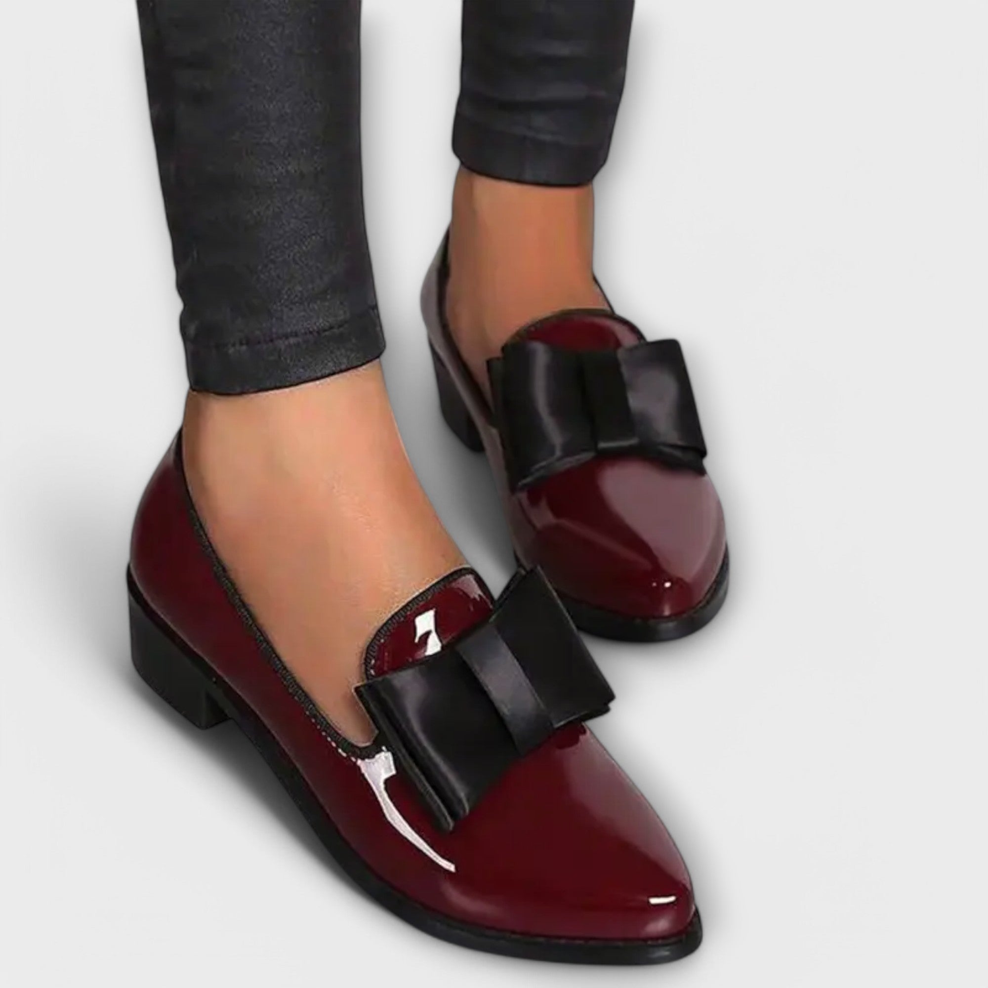 Chrysa glossy burgundy loafers with black strap buckle, worn with dark pants