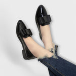Chrysa glossy black loafers with black strap buckle, worn with denim and ankle showing