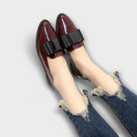 Chrysa glossy burgundy loafers with black strap buckle, worn with ripped denim