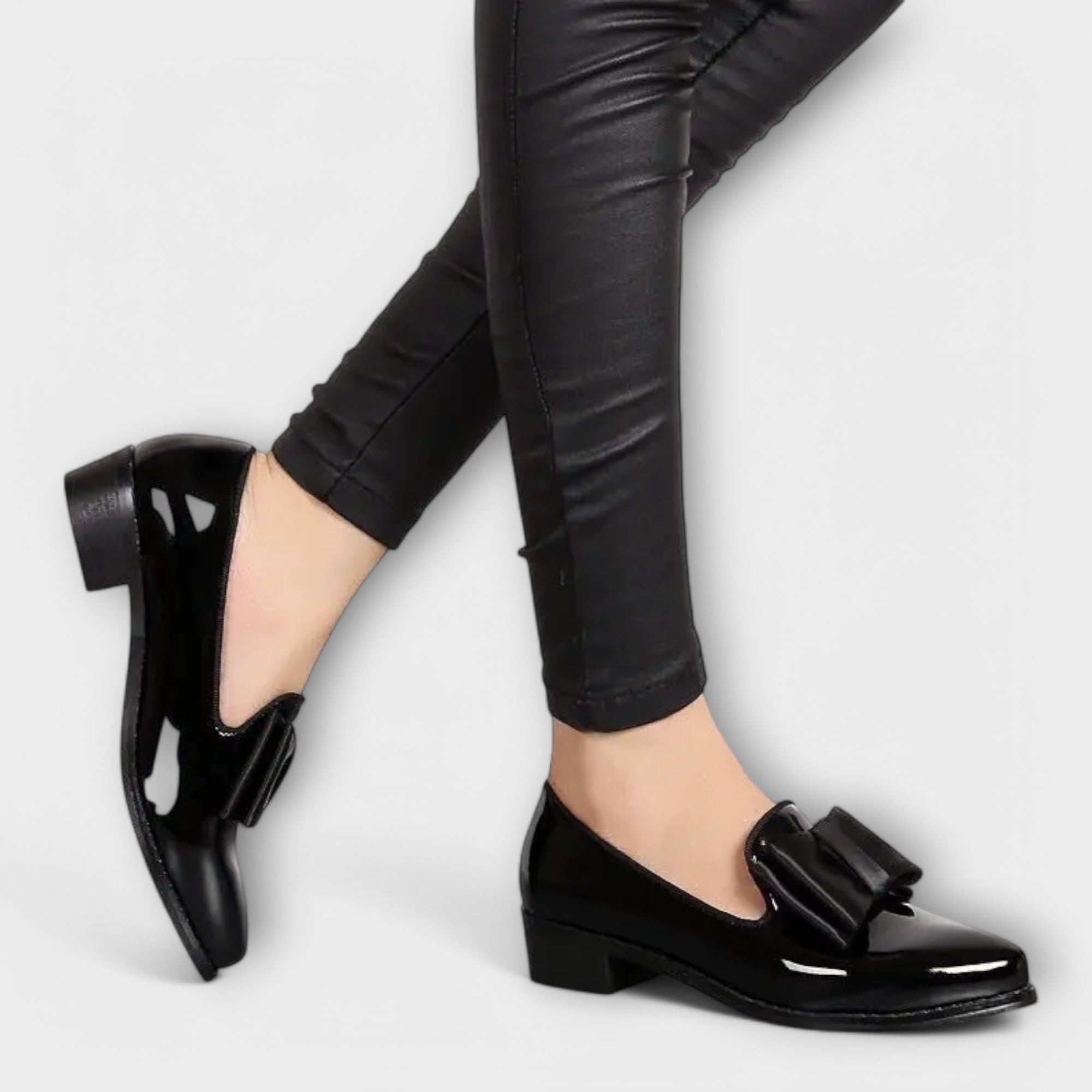 Chrysa glossy black loafers with black strap buckle, worn with black pants