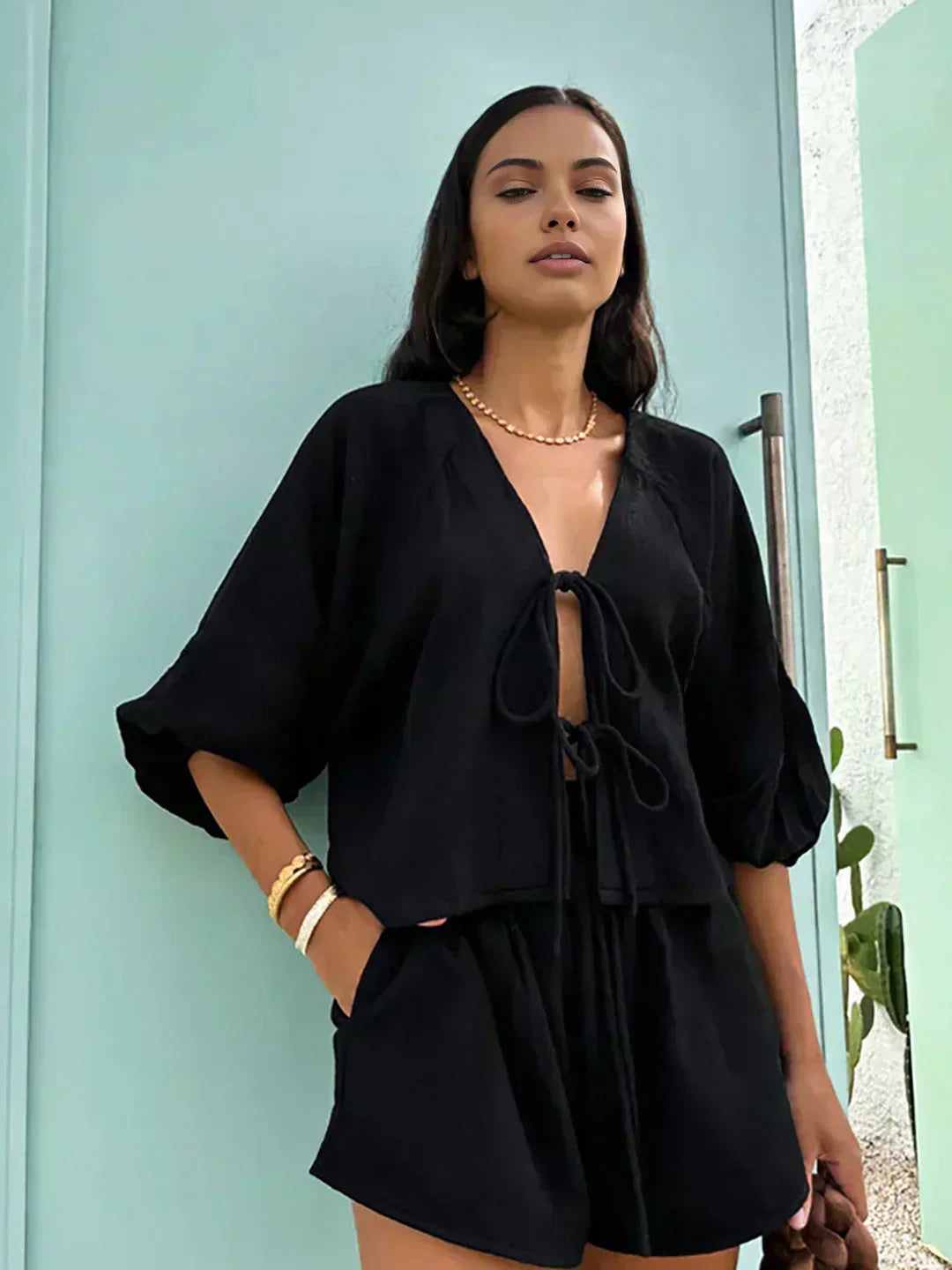 Black long-sleeve blouse with bow-tie neckline and matching black shorts