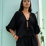 Black long-sleeve blouse with bow-tie neckline and matching black shorts