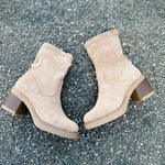 Pair of beige suede ankle boots with stacked low heels and pull-on opening