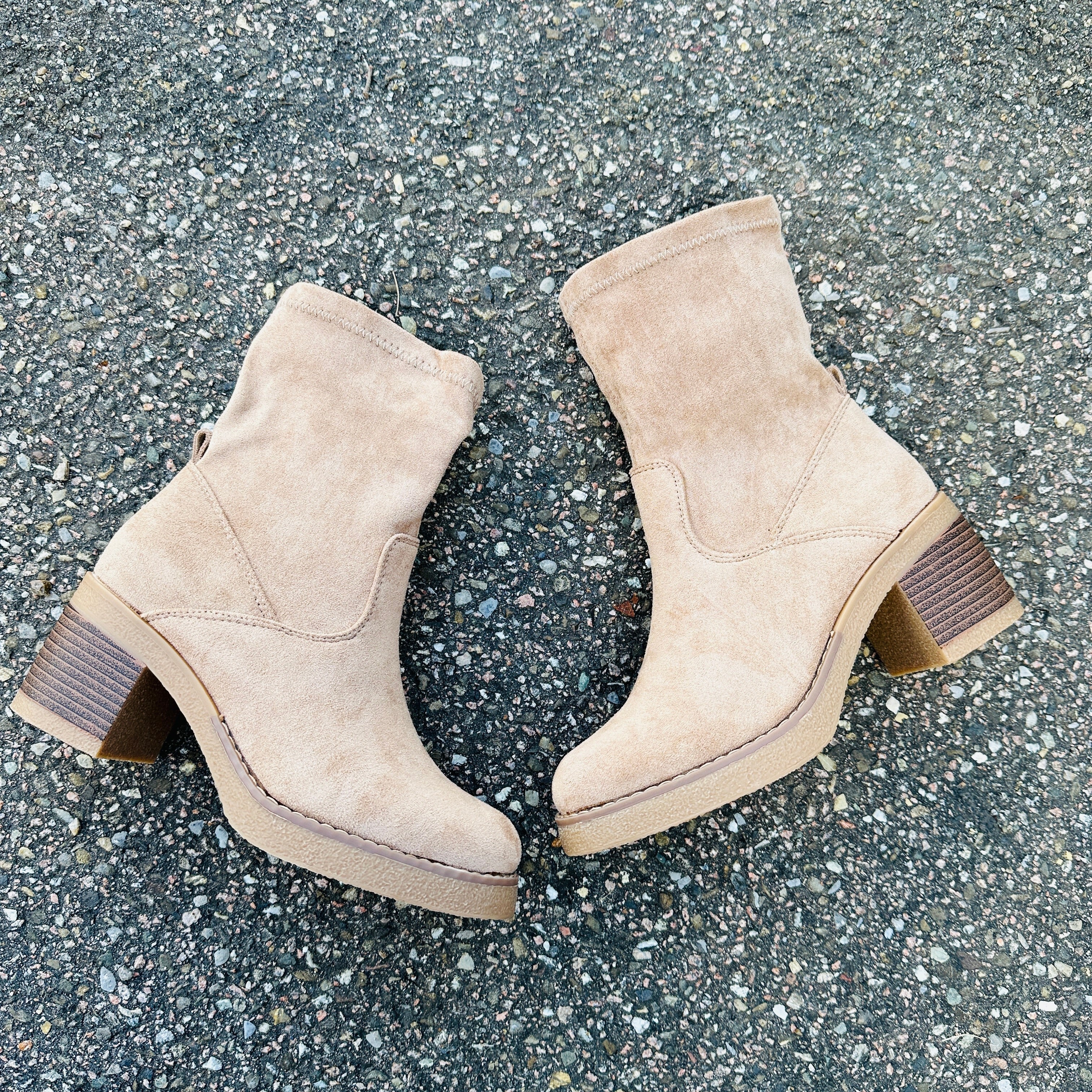 Pair of beige suede ankle boots with stacked low heels and pull-on opening