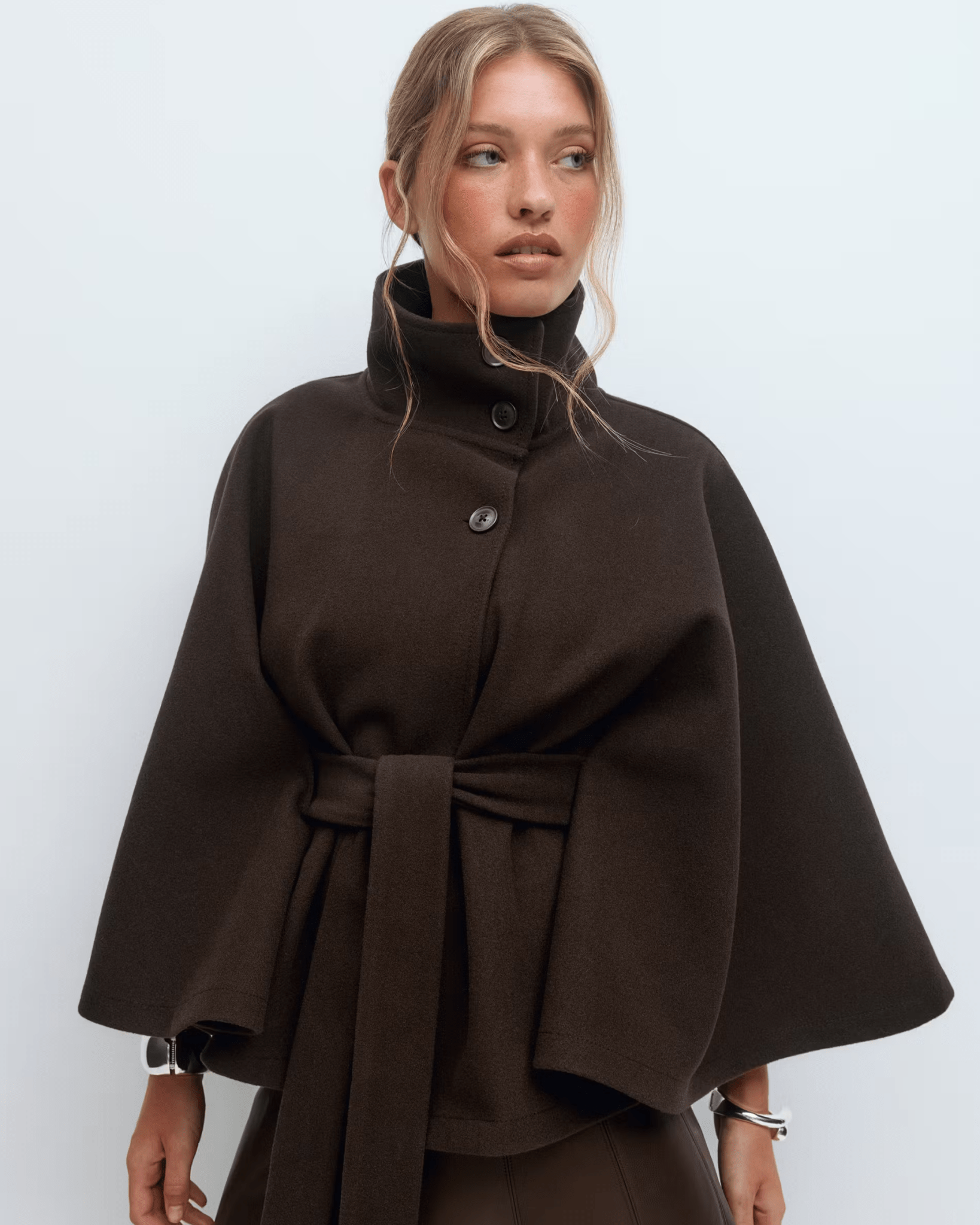 Dark brown belted jacket with high neck and button front, cape sleeves