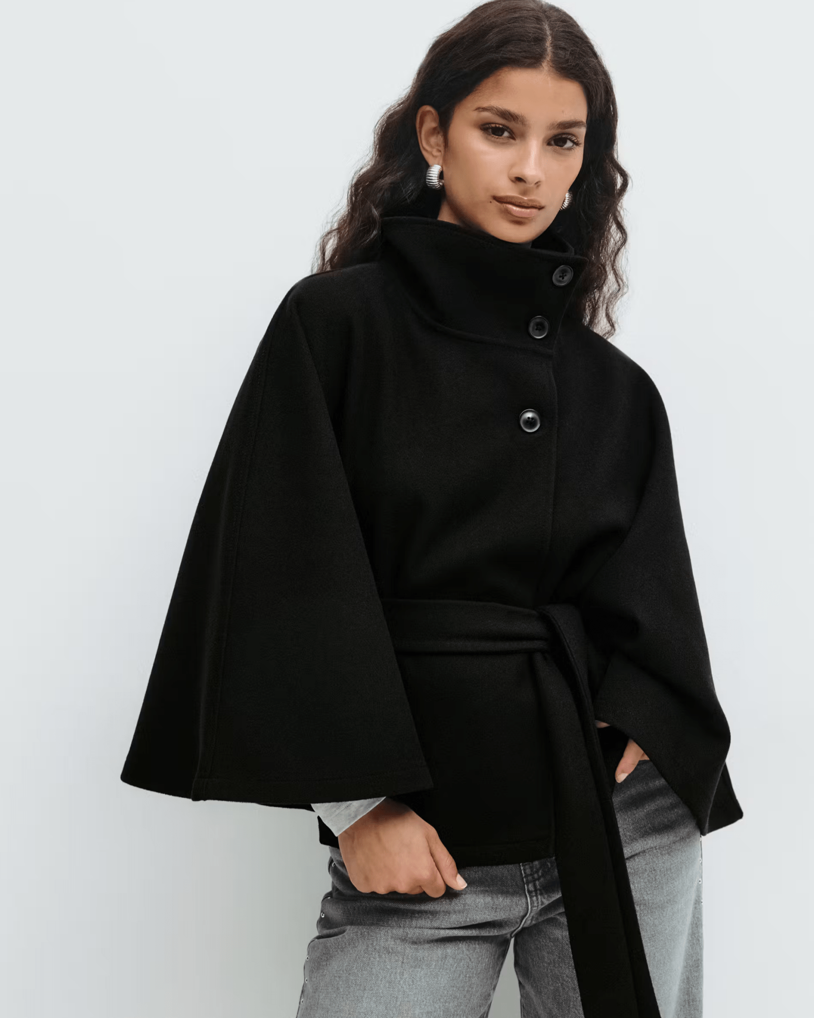 Black belted jacket with high neck and button front, cape sleeves