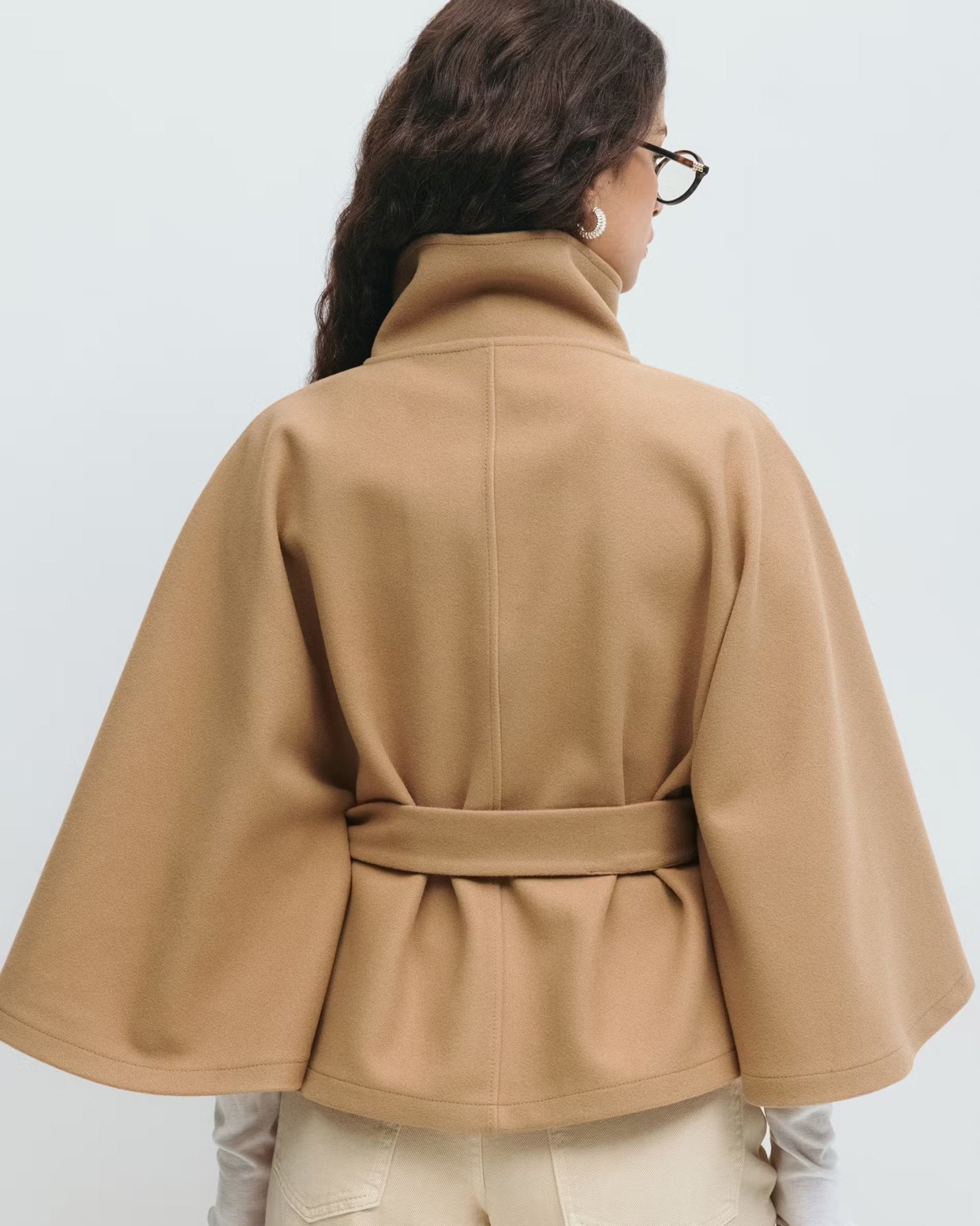 Camel back view of belted jacket with high neck and button placket