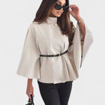 Light beige cape-style coat with high neck, button closure, and waist belt