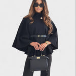 Black cape-style coat with high neck, round buttons, and gold-buckle waist belt