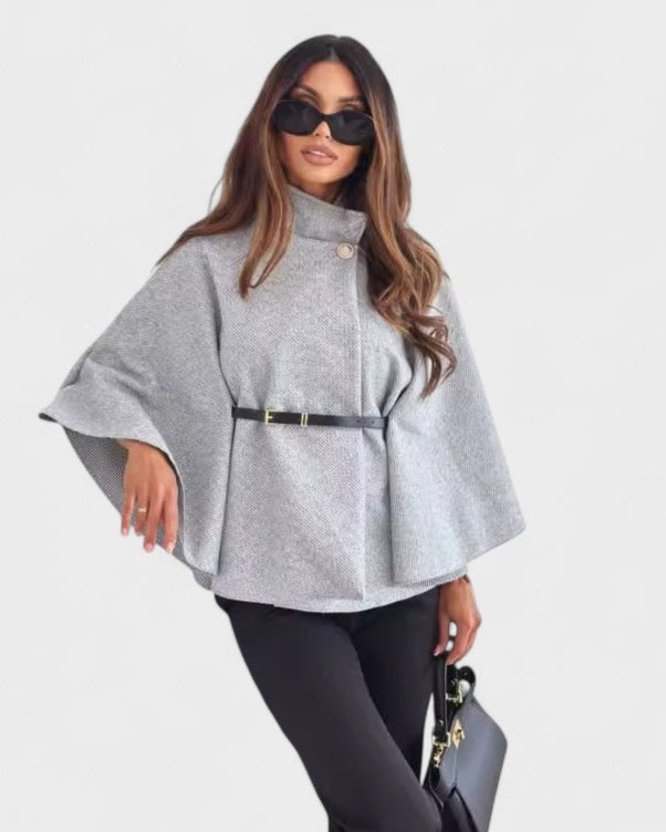 Light gray cape-style coat with high neck, button closure, and waist belt