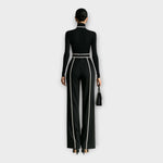 Women's black turtleneck jumpsuit with contrast piping, belt, back view