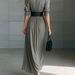Back view of long pleated grey dress with belted waist and three-quarter sleeves