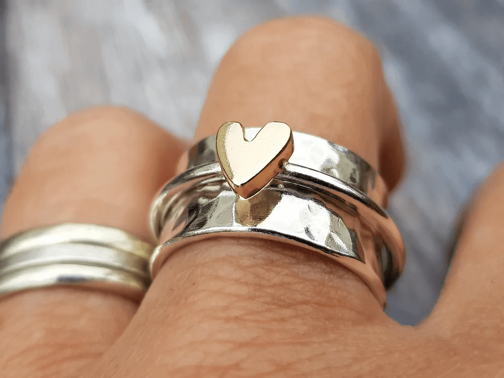 Layered silver ring with gold-tone heart top, worn on finger