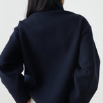 Back view of dark navy cropped jacket with buttoned shoulder detail