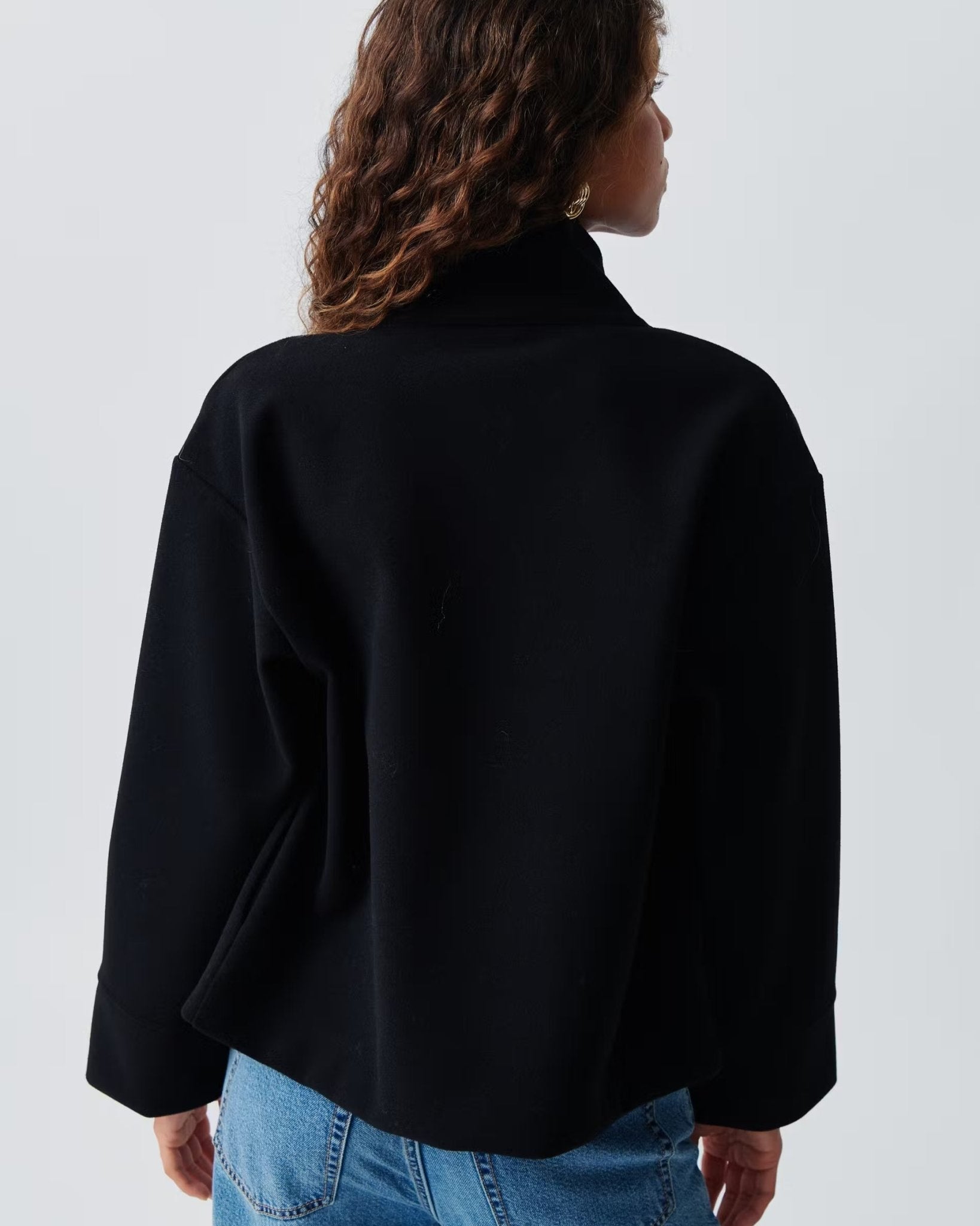 Back view of cropped dark navy jacket with high collar and loose sleeves
