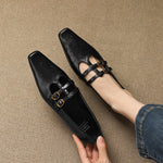 Pair of black Mary Jane flats with perforations and double buckle strap closure