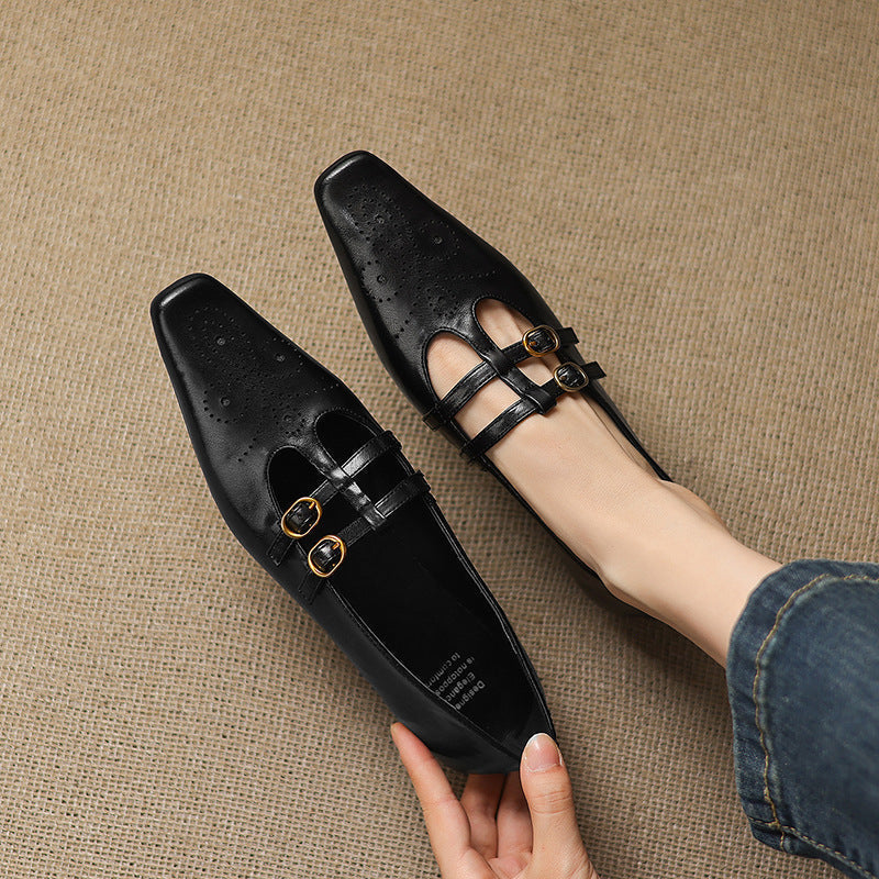 Pair of black Mary Jane flats with perforations and double buckle strap closure