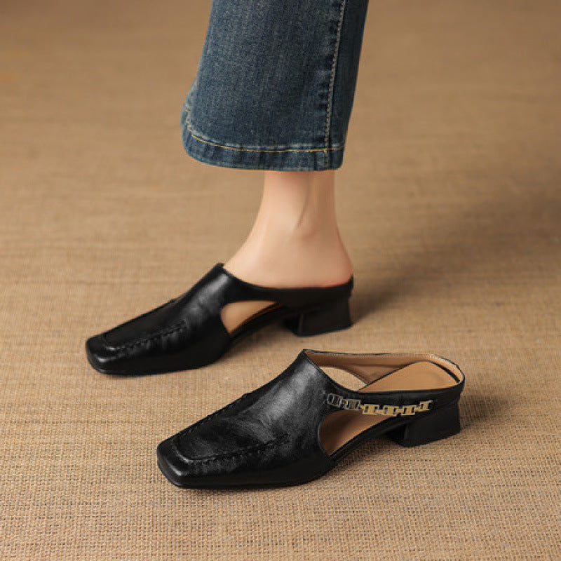 Black leather mule flats with square toe and low block heel, worn with jeans.