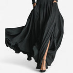 Black high-waist maxi dress with long sleeves, voluminous pleated skirt, and side slit