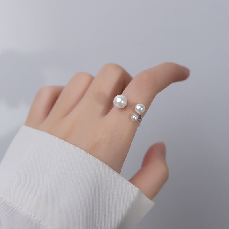 Silver triple-pearl adjustable ring worn on finger with three round pearls