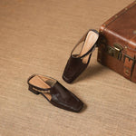Dark brown leather mule loafers with open toe and patterned strap on low heels