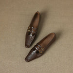 Brown Mary Jane flats pair on textured surface, perforated toe and two buckles