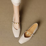 Cream leather ballet flats with gold buckle strap and rounded toe on a person