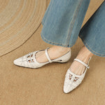 Cream Mary Jane flats with ankle strap and buckle, laced design, pointed toe on model.