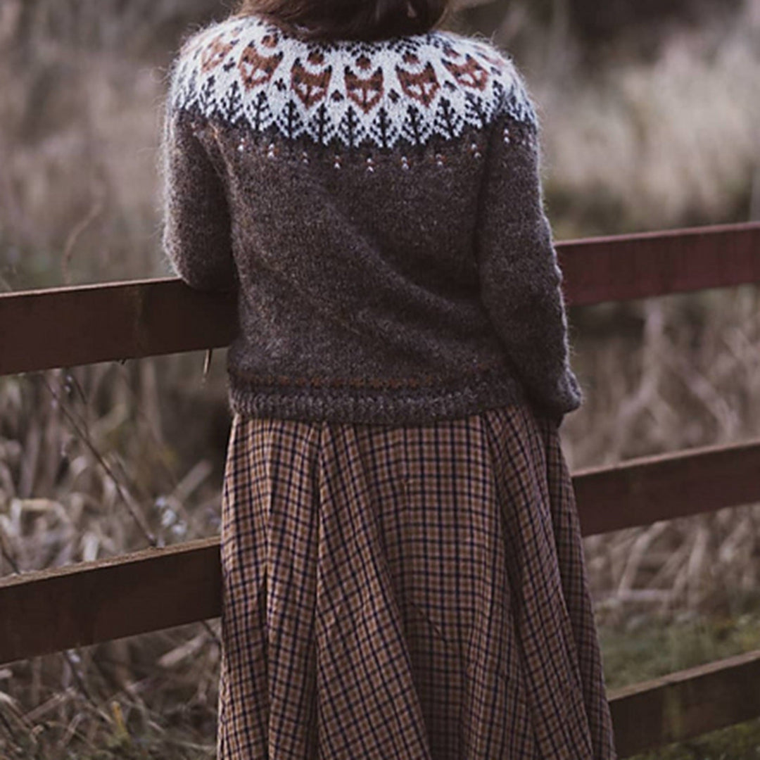 Fair isle knit pullover with crew neck and long sleeves, worn over plaid skirt.