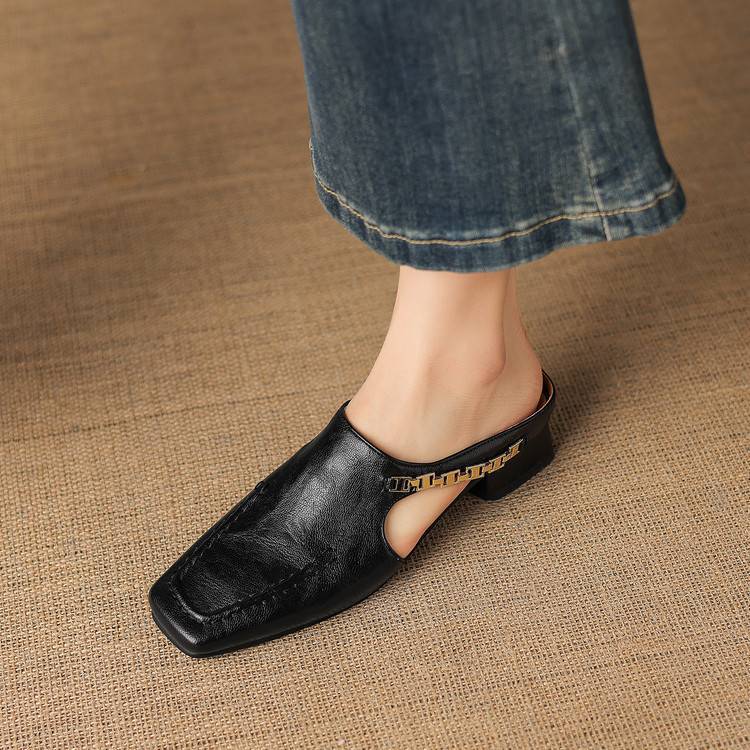 Black leather mule flat with cutout top strap and low block heel, side view.