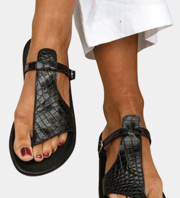 Black T-strap slide sandals with buckled ankle strap, textured upper