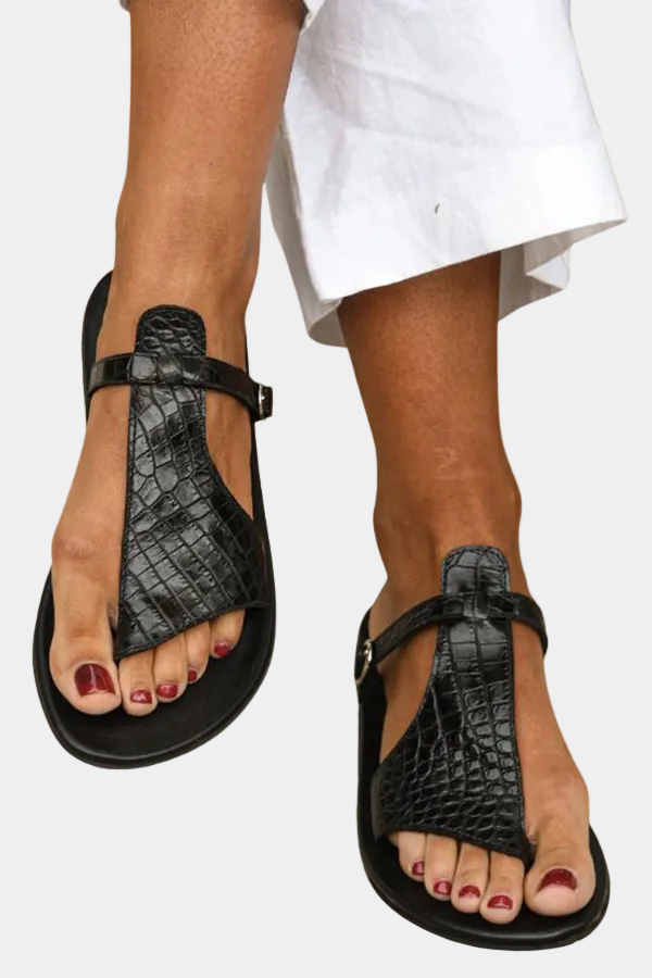 Black T-strap slide sandals with buckled ankle strap, textured upper