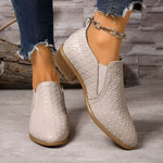 White textured ankle boots with chain strap, low block heel, and pointed toe