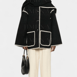 Black wool poncho-style coat with integrated scarf, white trim, flap pockets and fringe