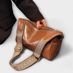 Tan retro crossbody bag with woven strap and gold-tone buckle, small structured shape.