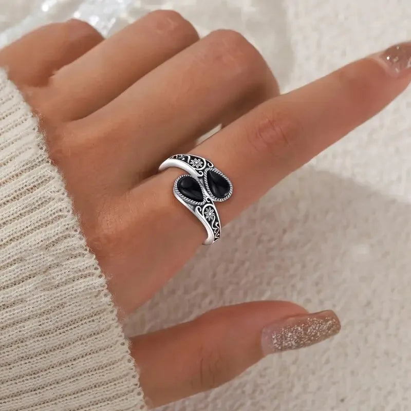 Silver-tone ring with two dark oval stones, ornate filigree sides, flower engravings