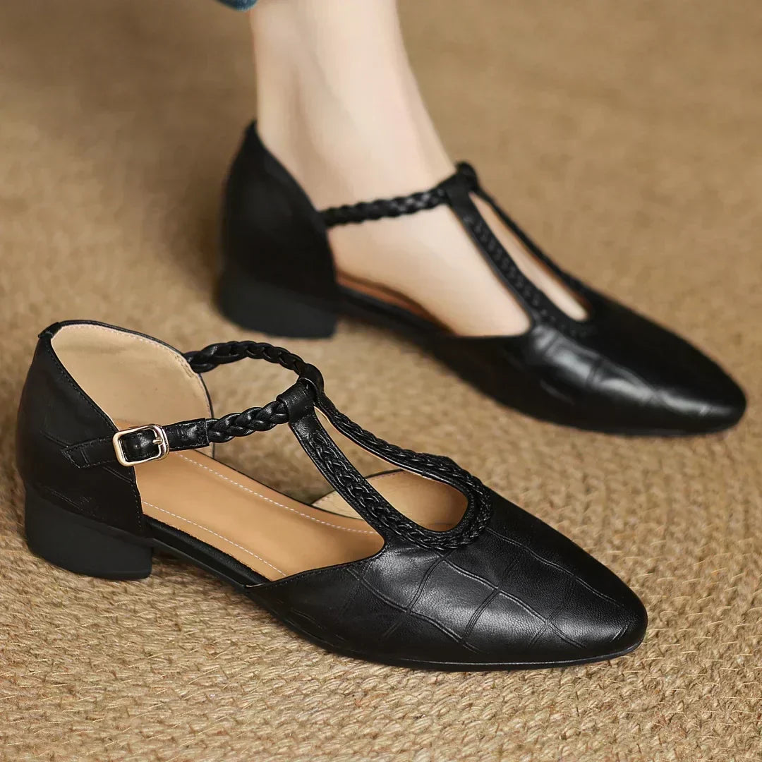 Black leather pointed-toe flats with braided ankle strap and gold buckle
