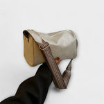 Beige retro crossbody bag with woven strap and zip top, compact side profile.