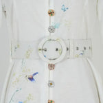 Waistband and button detail with decorative charms on a white-blue floral dress