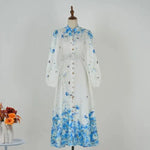 Blue floral midi dress on mannequin with high neck, long sleeves and tie belt
