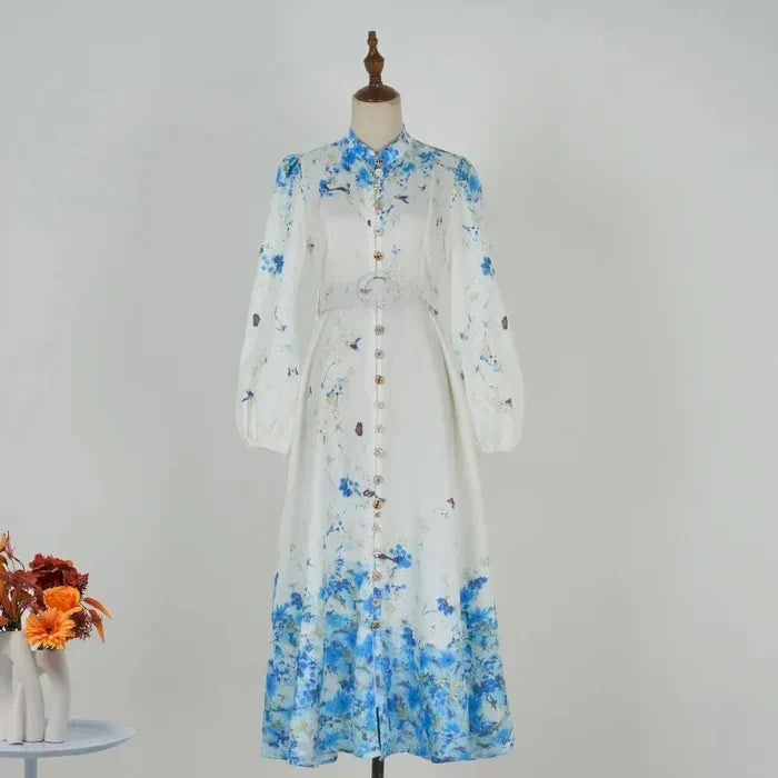 Blue floral midi dress on mannequin with high neck, long sleeves and tie belt