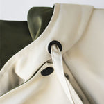 Snap closure detail on two-tone parka jacket, black button on cream trim