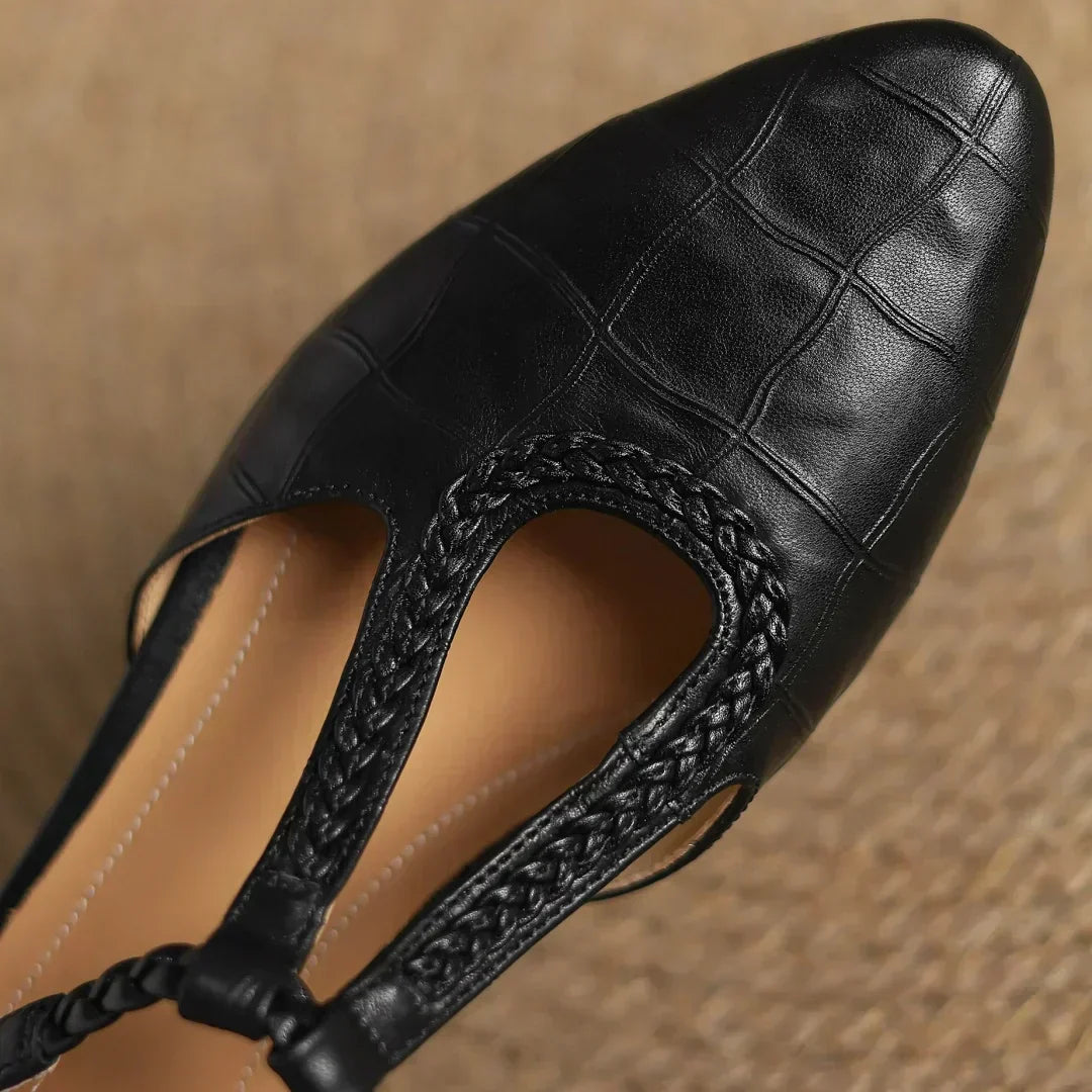 Black leather T-strap mary jane with textured trim and openwork cutout