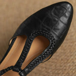 Black leather T-strap mary jane with textured trim and openwork cutout